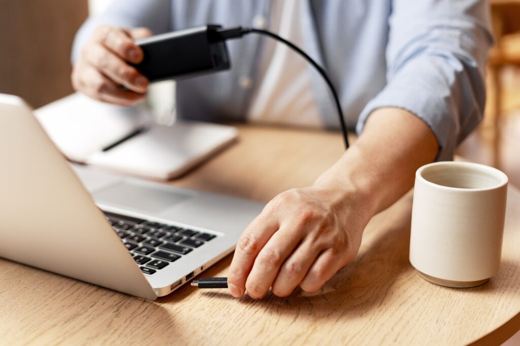 Businessman connecting external hard drive to laptop for file transfer